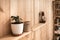 White pot with ivy plant and wicker box on wooden shelf. Retro lantern on blurred background. Wooden wallpaper panels