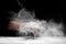 White powdery flour spraying into air while man hand baker cook on black background