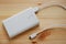 White power bank or backup battery with USB 2.0 cable charger on wooden background.Top view