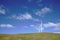 White power generating windmills on grassy mound under blue sky