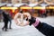 White pretzel in hand against background of street food stalls