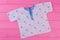White printed shirt for newborn baby on pink background.