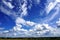 White puffy clouds in blue sky, agricultural landscape