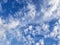 White, puffy clouds in blue sky with jet and con trail