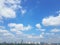 White puffy cumulus clouds over cityscape with blue skies