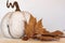 White pumpkin, dry leaves and acorn. Autumn concept