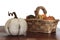 White pumpkin on wooden table with assortment of pumpkins on basket on the background