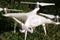 White quadcopter Drone with 4K digital camera on grass is ready for take off to fly in air to take photos, record footage.