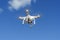 White quadcopter soars easily in blue sky