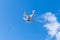 White quadrocopter in blue cloudy sky