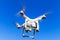 White quadrocopter flying in blue sky, closeup photo