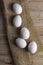White and quail eggs stand on a burlap on a wooden table