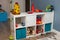 White rack with children`s toys in the playroom