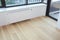 White radiator heating with thermostat for energy saving, wooden floor in the modern empty room.