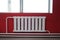 White radiator for indoor heating against a background of red walls. Modern bright interior.
