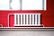 White radiator for indoor heating against a background of red walls. Modern bright interior.