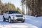 White Range Rover Evoque with a black roof on a winter road in the forest of the Samara region, Russia. Clear Sunny day