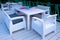 white rattan wicker armchairs and tables on summer terrace in twilight