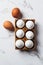 White raw chicken eggs in brown stand on a white marble background