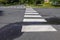 White rectangular intermittent crosswalk markers painted on the asphalt road in a residential neighborhood