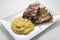 White rectangular plate with baked pork ribs and cornmeal mush