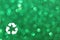 White recycle sign and green glitter lights background. defocused lights.