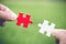 White and red jigsaw puzzles in the hands of a businessman Green natural background Business concept Organization collaboration