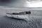 A white and red painted wooden fishing boat on the Paternoster beach in South Africa in black and white