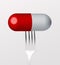 White and red pill on fork on gray background