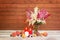 White, red and pink beautiful astilbe flowers in glass vase, burning candles and fresh fruits near  on aged wooden table