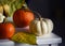 White and red pumpkins and yellow leaves in a dark interior.