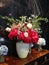 White and red rose many Flowers in white vase on wooden desk