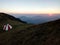 White and red shelter on a mountain ridge during sunrise