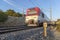 White and red short distance train in motion when leaving a tunnel and with a kilometric road sign