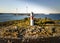 White red striped sea beacon on stone island with two windmills behind for safe navigation in baltic sea