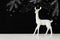 White reindeer on wooden table over chalkboard background whith hand drawn chalk illustrations