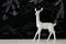 White reindeer on wooden table over chalkboard background whith hand drawn chalk illustrations.