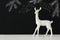 White reindeer on wooden table over chalkboard background whith hand drawn chalk illustrations.