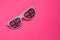 White rimmed sunglasses with UK flag on pink isolated background. Free space for text