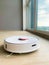 White robot cleaner. Robot vacuum cleaner on laminate floor in action