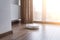 White robot cleaner on a wooden floor near the panoramic window