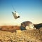 White robot drone hovering over obsolete space helmet in cracked desert on other planet. sci-fi concept 3d render