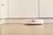 White robot vacuum cleaner cleans the floor from debris,home cleaning with an electric vacuum cleaner,vacuum cleaner electric