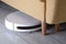 White robot vacuum cleaner removes dust under the sofa
