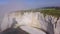 White rock with arch and misty coast. Action. Top view of picturesque panorama of coastal cliff immersed in light fog on