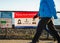 White Rock, Canada - March 25, 2020: Two pedestrians walking past Covid-19 social distancing sign