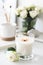 White room interior decor with burning hand-made candle and bouq