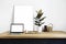 White room interior with green plants on rustic wooden table, modern personal laptop, poster in frame with space for layout