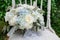 White rose and blue hydrangea wedding bouquet on rustic chair with greenery background