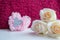 White rose buds against the background of fluffy pink heart-shaped pompom